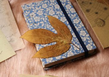 Flat lay con materiales de junk journal: cuaderno hecho a mano, papeles vintage, hojas secas y herramientas