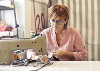 mujer aprendiendo a usar una máquina de coser para principiantes en un taller de costura luminoso