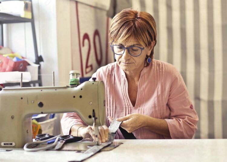 mujer aprendiendo a usar una máquina de coser para principiantes en un taller de costura luminoso