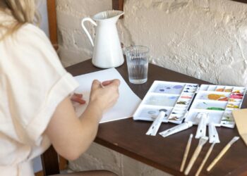 mujer creando cuadros decorativos DIY con pinturas acrílicas sobre lienzo en su taller