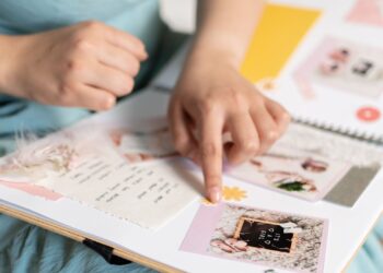Manos creando un scrapbooking de cumpleaños con fotos y adornos