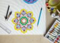 Materiales para dibujar mandalas: lápices, compás y un mandala sobre la mesa