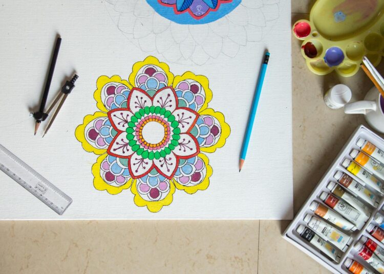 Materiales para dibujar mandalas: lápices, compás y un mandala sobre la mesa