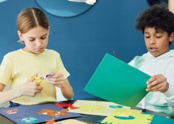 Niños haciendo manualidades con platos de cartón en una mesa