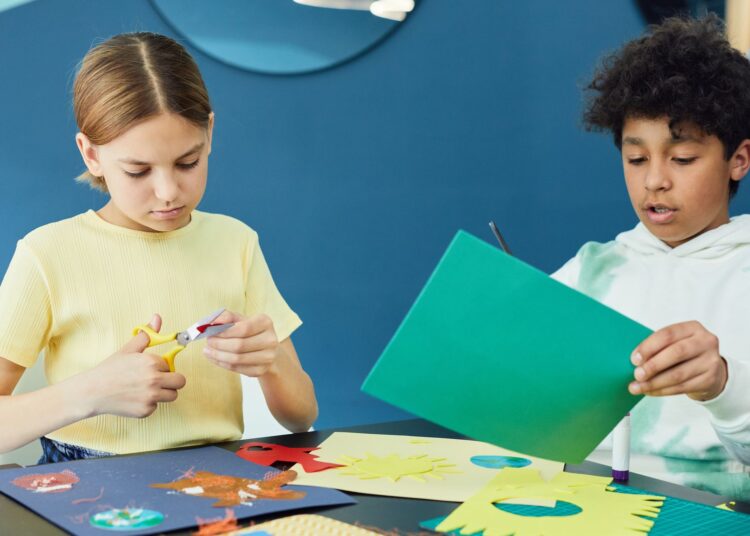Niños haciendo manualidades con platos de cartón en una mesa
