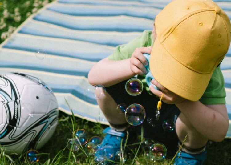 Niño soplando pompas de jabón caseras al aire libre en verano