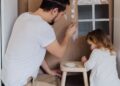 Padre e hija pintando manualidades con hueveras y cartón reciclado en casa