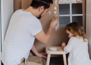 Padre e hija pintando manualidades con hueveras y cartón reciclado en casa