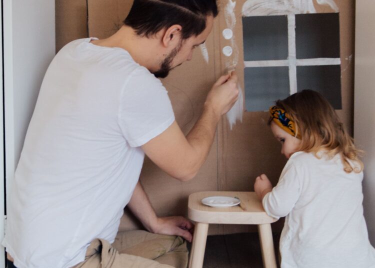 Padre e hija pintando manualidades con hueveras y cartón reciclado en casa