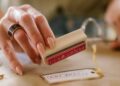 Manos estampando una tarjeta con sellos caseros sobre una mesa de manualidades