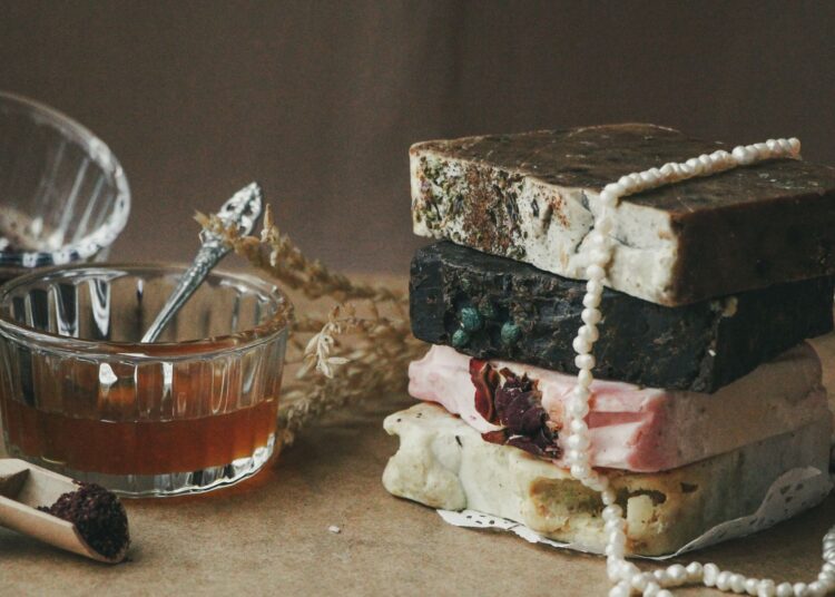 Pastillas de jabón casero artesanal apiladas sobre madera con ingredientes naturales