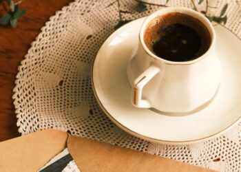 Cartas de papel envejecido junto a una taza de café sobre madera, técnica para envejecer papel