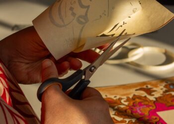 Manos cortando papel decorativo con cuchilla de precisión para practicar kirigami