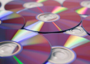 Discos compactos apilados con reflejos de arcoíris, base para manualidades con CDs recicladas
