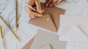 Sobres de papel hechos a mano sobre una mesa con lápiz y papel de manualidades