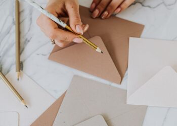 Sobres de papel hechos a mano sobre una mesa con lápiz y papel de manualidades