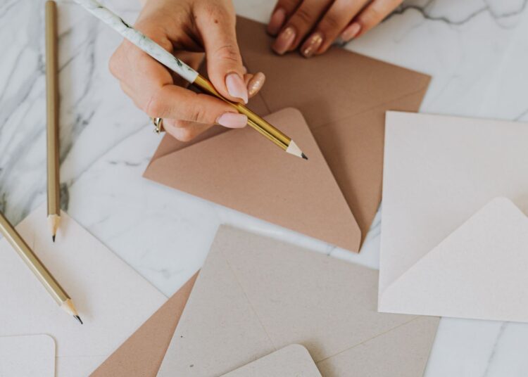 Sobres de papel hechos a mano sobre una mesa con lápiz y papel de manualidades