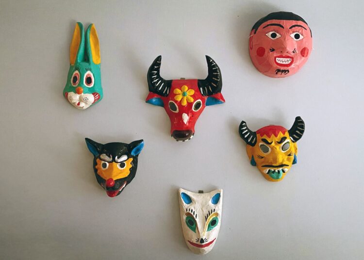 Máscara artesanal de papel maché colgada en una pared, ejemplo de pieza terminada