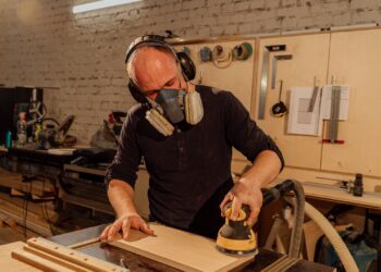 Manos lijando una tabla de madera con papel de lija sobre un banco de taller