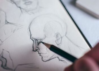 Mano dibujando ojos a lápiz sobre papel blanco en un cuaderno de bocetos