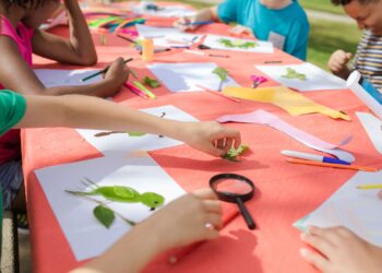 Niños creando con materiales de kits de manualidades para niños sobre una mesa de trabajo