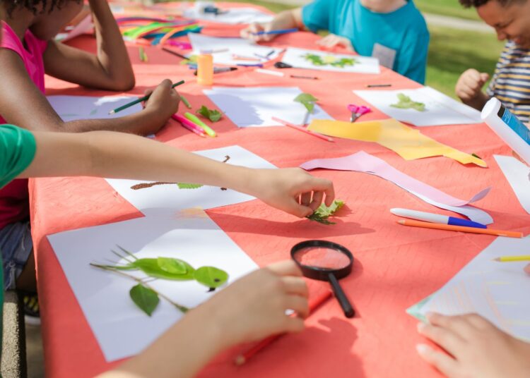 Niños creando con materiales de kits de manualidades para niños sobre una mesa de trabajo