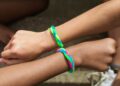 Primer plano de dos muñecas con varias pulseras de hilo de colores hechas a mano