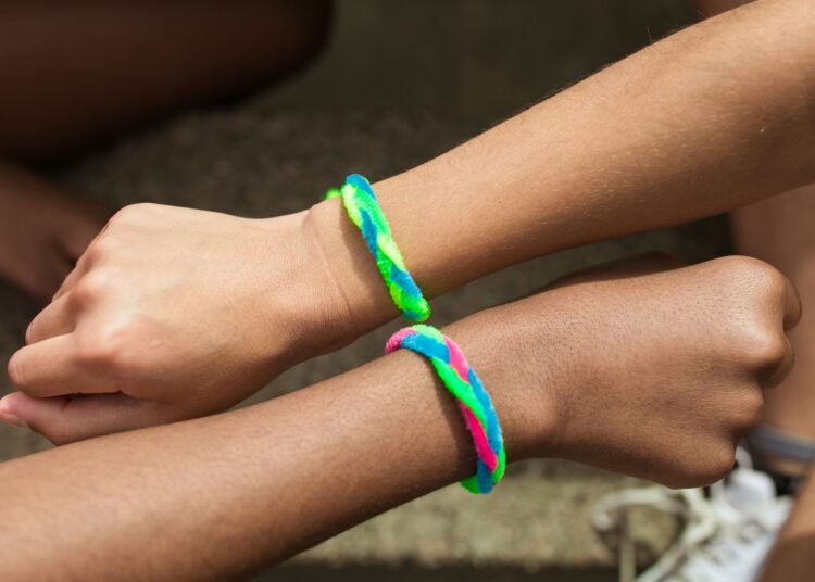 Primer plano de dos muñecas con varias pulseras de hilo de colores hechas a mano