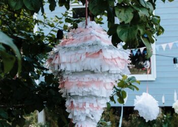 Piñata casera de colores colgada de un árbol lista para una fiesta infantil