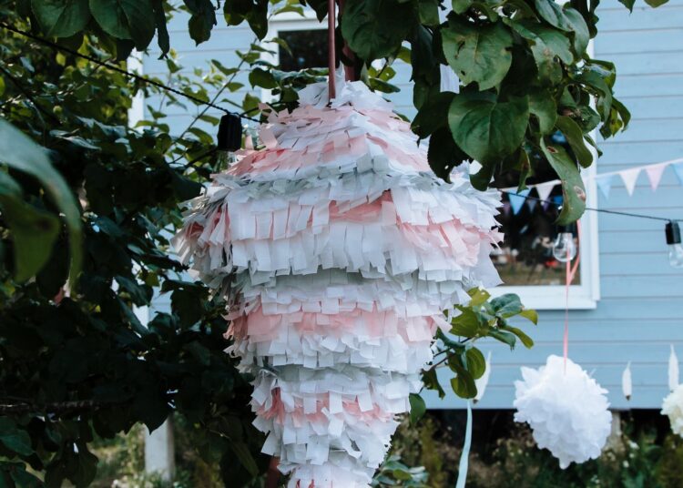 Piñata casera de colores colgada de un árbol lista para una fiesta infantil