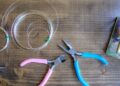 Pinzas y bobinas de alambre sobre una mesa para hacer joyas con alambre paso a paso