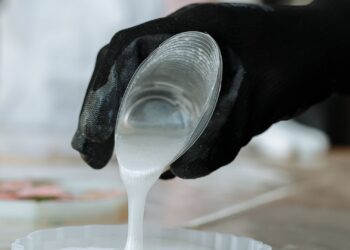 Manos con guantes vertiendo silicona líquida para hacer moldes de silicona caseros