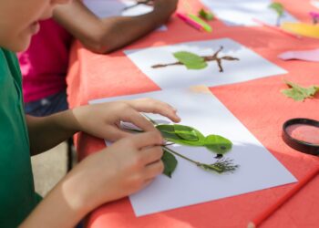 Niño haciendo manualidades de otoño con hojas secas de colores sobre una mesa