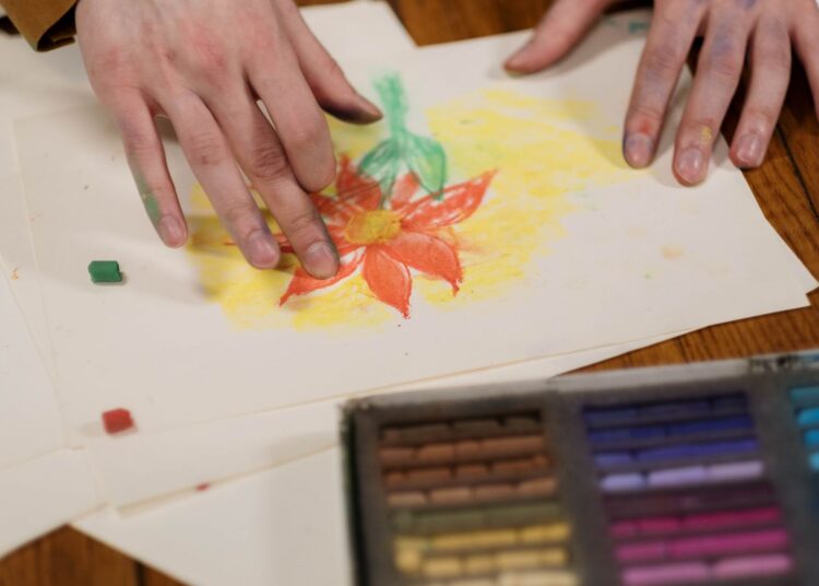 Persona dibujando una flor a lápiz en un cuaderno, ejemplo de cómo dibujar flores paso a paso